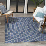 Modern patio scene with a Nourison Twist Blue Area Rug, wood furniture, and blue accent pillows.
