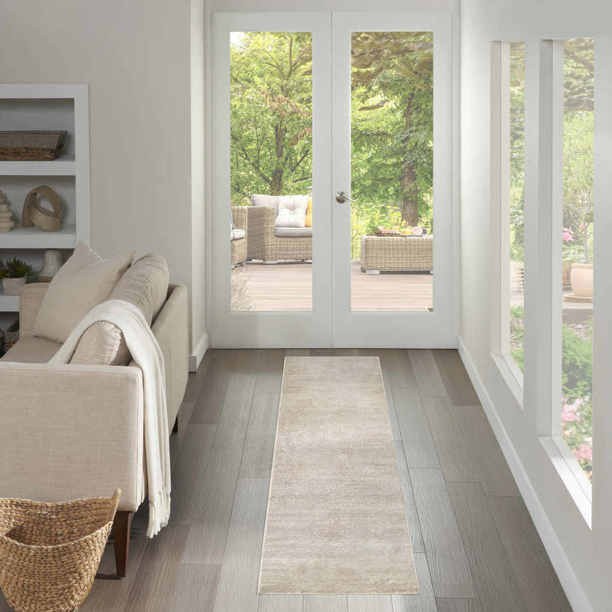 Light-filled hallway with a Nourison Serenity Home Ivory rug, leading to an outdoor patio. Neutral tones create a serene atmosphere.