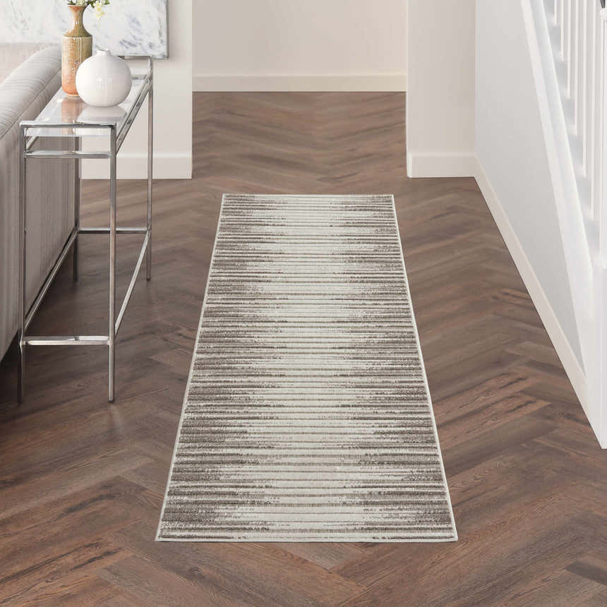 Hallway scene with Nourison Key Largo Light Grey rug, wood floors, console table, and neutral decor. Contemporary style.