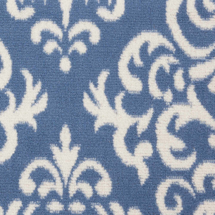 Close-up of Nourison Grafix Blue Vintage Area Rug. Features a light blue background with a detailed white floral pattern.