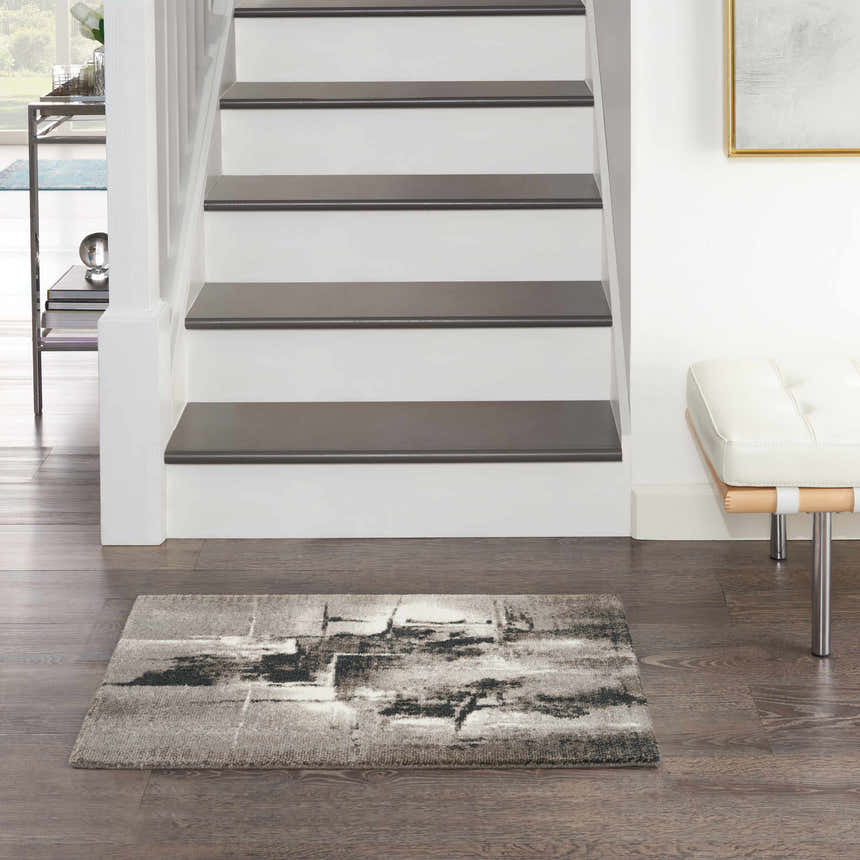 Entryway with Nourison Twilight Grey Ivory Black Rug, stairs, wood floors, and white bench.