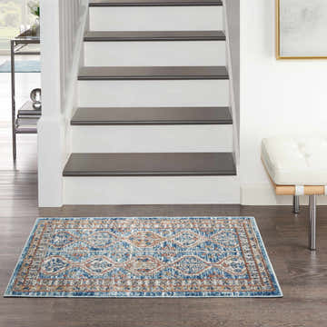 Entryway with Nourison Quarry Blue Multicolor rug, white stairs, and a modern white bench.