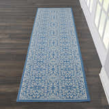 Hallway scene with Nourison Jubilant Ivory Blue rug runner on dark wood floor, next to white trim and window.