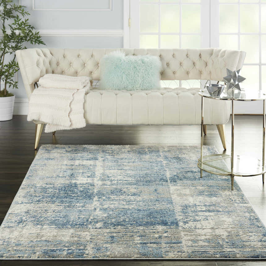 Living room scene with a Nourison Solace Ivory Grey Blue rug, cream sofa, and gold accents for a modern, airy feel.