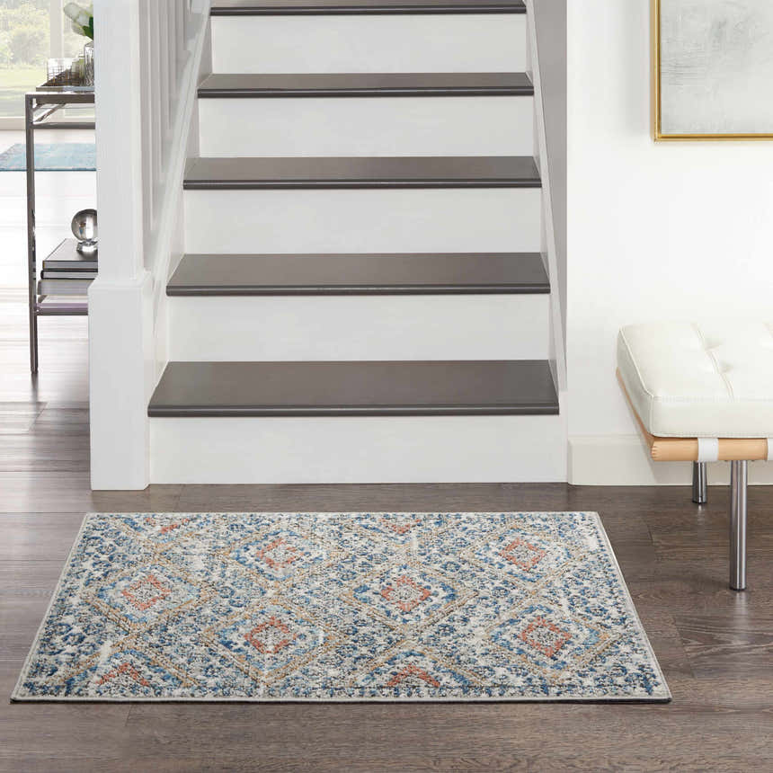 Entryway with Nourison Quarry Blue Ivory Southwestern rug, wood floors, white stairs, and modern bench.
