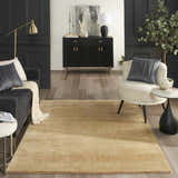 Living room scene with a Nourison Plush Cloud Camel rug, gray sofa, and cream accent chair. Modern, neutral tones.