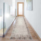 Bright hallway with a Nourison Elation Ivory Grey runner rug, wood floors, glass railing, and white walls.