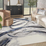 Living room scene with a Nourison Splash Grey Navy rug, beige sofa and chair, and modern decor.