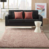 Living room scene with a Blush Shag rug, gray sofa, pink pillows, and a city view. Boutique Rugs.