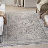 Living room scene with a Nourison Lynx Ivory Charcoal Vintage Area Rug, white sofa, and rattan chair.