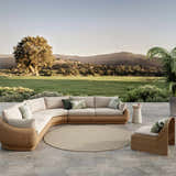 Outdoor patio scene with a round Nourison Courtyard Jute Ivory rug, wicker furniture, and scenic mountain view.