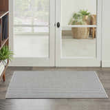 Farmhouse entryway with Nourison Natural Texture Ivory Grey rug on wood floor near white doors.