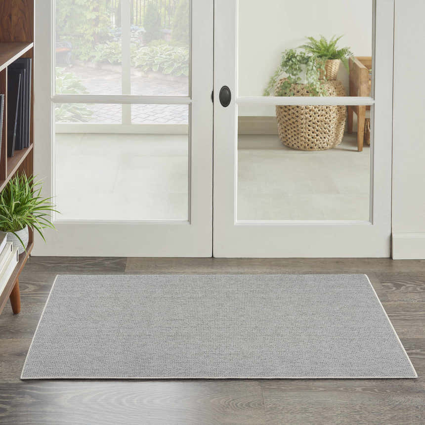Farmhouse entryway with Nourison Natural Texture Ivory Grey rug on wood floor near white doors.