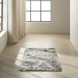 Minimalist room scene with a Calvin Klein San Antonio charcoal ivory shag rug on light wood floors near a window.