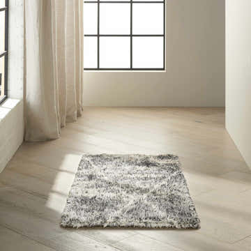 Minimalist room scene with a Calvin Klein San Antonio charcoal ivory shag rug on light wood floors near a window.