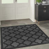 Entryway with a Nourison Easy Care Charcoal Black Modern Area Rug, black cabinet, and white door.