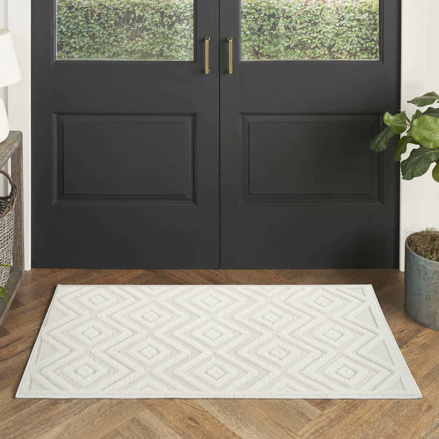Entryway with black door and Nourison Versatile Ivory White Modern Area Rug with geometric diamond pattern on wood floor.