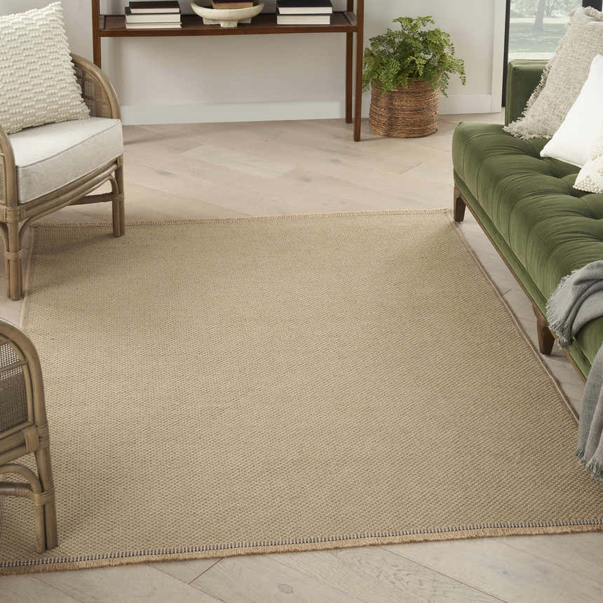 Living room scene with a Nourison Jute Natural rug, green sofa, and light wood floors. Modern, neutral tones.