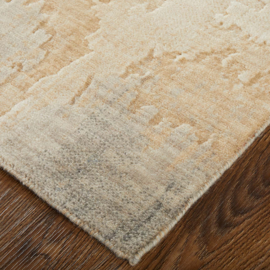 Close up of Feizy Jaxson rug showing distressed tan, brown, and gray geometric pattern and wool texture on wood floor. Corner