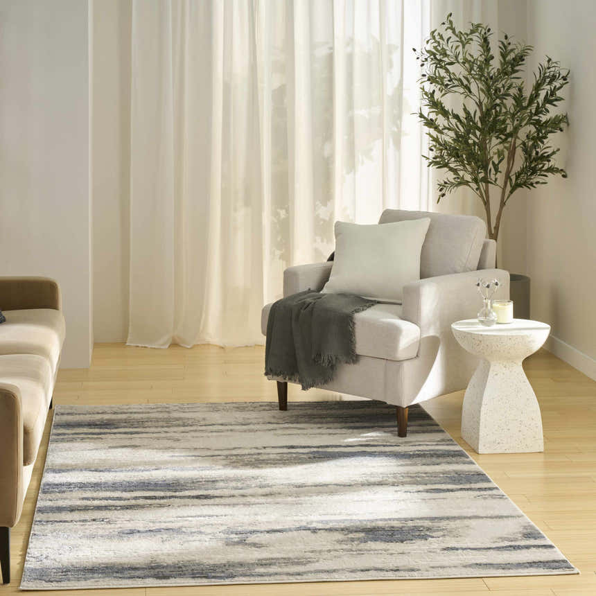 Living room scene with a Nourison Serenity Home Blue Multicolor rug, neutral sofa and armchair, and bright natural light.
