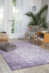 Sunlit room with Nourison Silk Shadows Amethyst rug, vintage style. Features a chair, side table, and a calming, neutral palette.