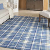 Living room scene with a blue plaid Nourison Grafix area rug, beige sofa, and white accent chair.