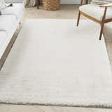 Living room scene with a Nourison Modern Shag Ivory rug, white sofa, wood chair, and light wood floors.