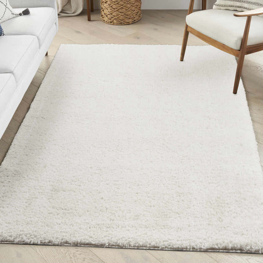 Living room scene with a Nourison Modern Shag Ivory rug, white sofa, wood chair, and light wood floors.