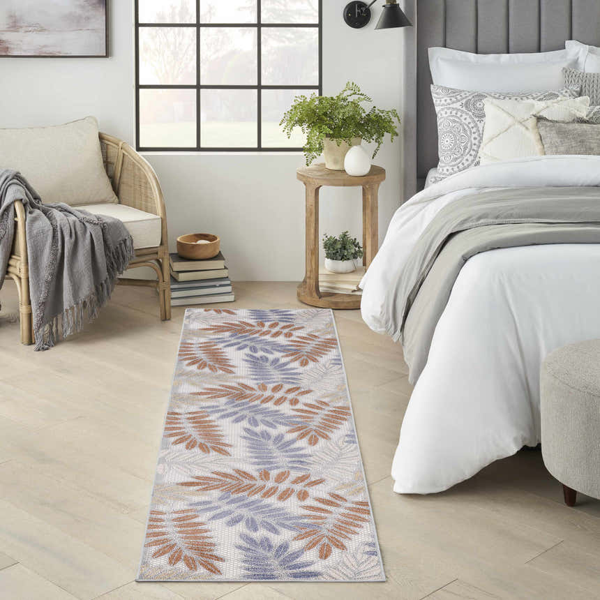Bedroom scene with Nourison Aloha Blue Mocha runner rug, rattan chair, and gray accents.