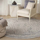 Living room scene with a round Nourison Lynx Ivory Grey Blue Vintage Area Rug, chair, and ottoman.