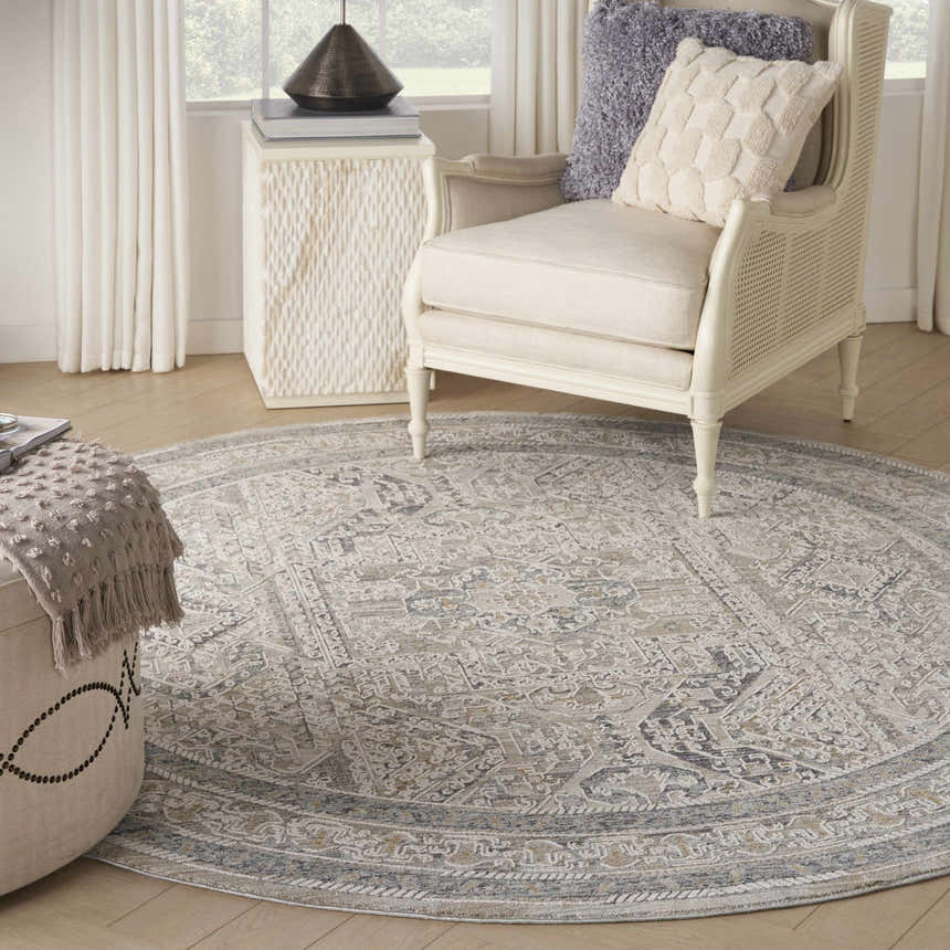 Living room scene with a round Nourison Lynx Ivory Grey Blue Vintage Area Rug, chair, and ottoman.