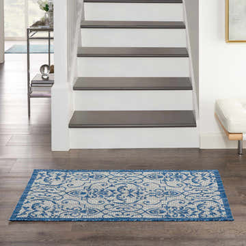 Entryway with Nourison Country Side Ivory Blue Farmhouse Area Rug on dark wood floors near stairs.