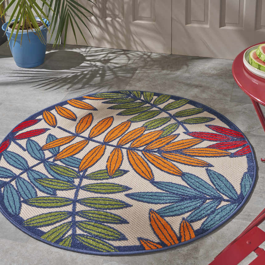 Patio scene with a round Nourison Aloha Multicolor Tropical Area Rug featuring a colorful leaf pattern.