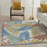 Living room scene with a Nourison Aloha Ivory Multicolor Tropical Area Rug, sofa, and chair.