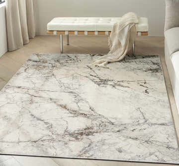 Modern living room with a Calvin Klein CK073 Compass Ivory Multicolor Area Rug, white bench, and light wood floors.