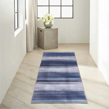 Hallway scene with a Calvin Klein Launder Navy rug. Modern, light-filled space with wood floors and a striped navy runner rug.