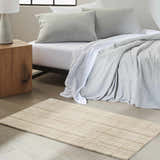 Bedroom scene with Calvin Klein CK041 Architectura Natural Farmhouse rug, wood nightstand, and gray bedding.