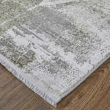 Close-up of Feizy Cadiz rug. Gray, green, and silver ikat pattern with fringe detail on wood floor. Modern, transitional style. Corner