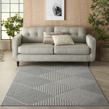 Living room scene with light gray sofa and the Nourison Cozumel Light Grey rug with geometric pattern.