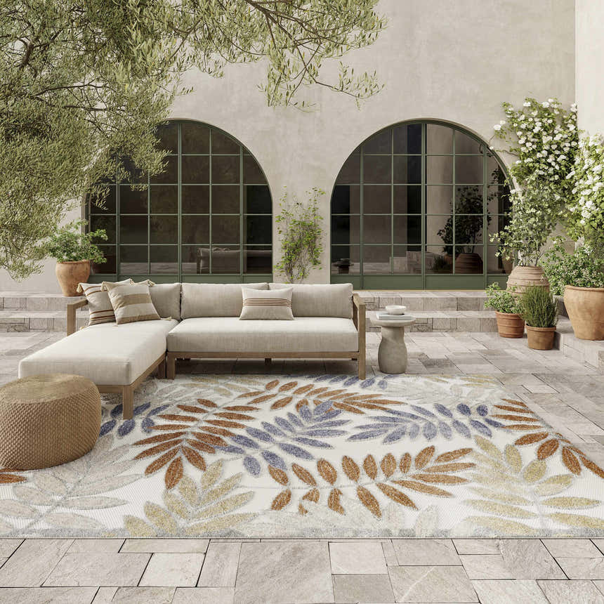 Outdoor patio with sectional and Nourison Aloha Blue Mocha rug with leaf pattern in blue, mocha, and cream.