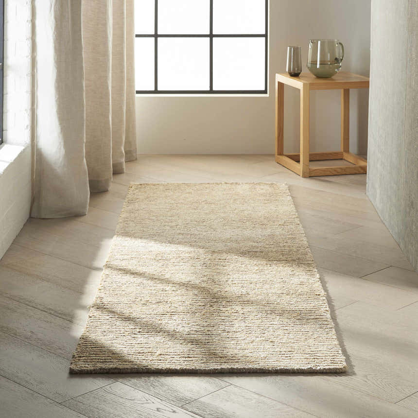 Minimalist room scene with a Calvin Klein Mesa Gypsum rug, wood floors, and neutral decor.