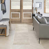 Entryway with a Nourison Serenity Home Ivory rug runner, gray leather sofa, wood doors, and herringbone floors.