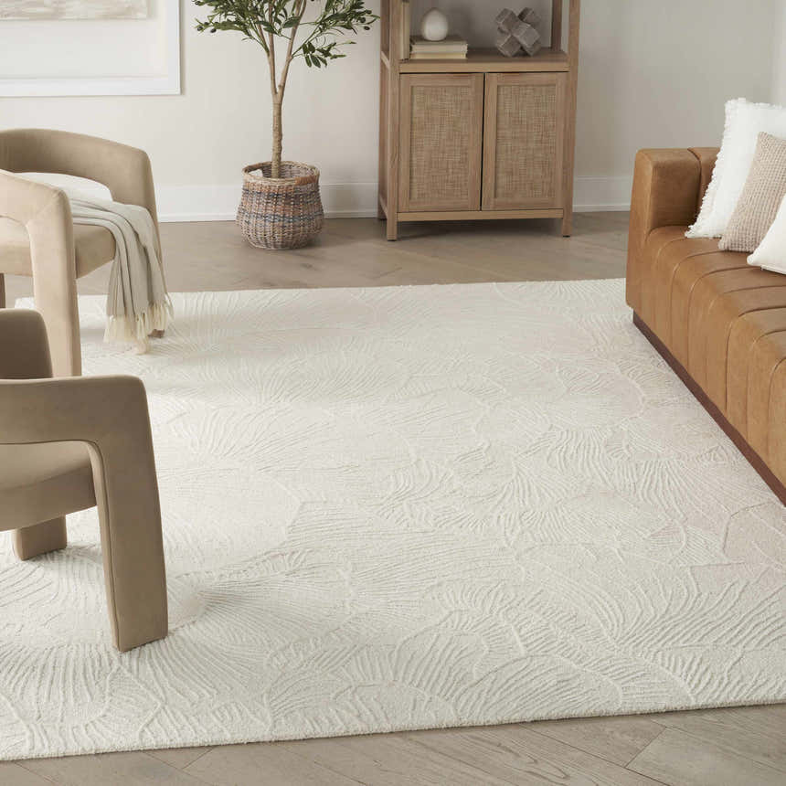 Living room with a chestnut leather sofa, beige chairs, and Nourison Avra Ivory Modern Area Rug.
