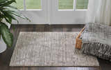 Entryway with ash Nourison OCEAN rug, dark wood floor, white door, plant, and throw blanket.