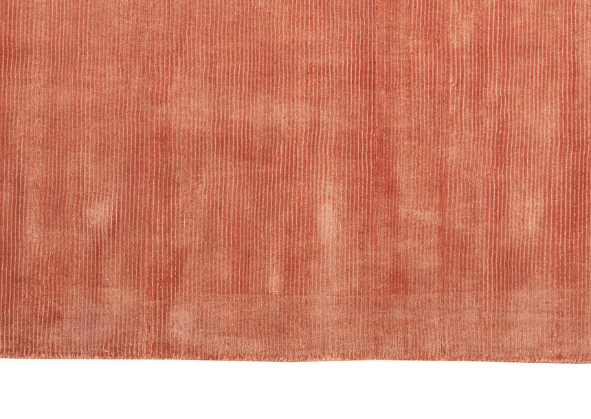 Close-up of the Calvin Klein Home Lunar Rust rug, showing its soft texture and subtle vertical stripe pattern.