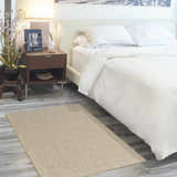 Bedroom scene with a Nourison Courtyard Jute Ivory rug, white bedding, and a dark wood nightstand.
