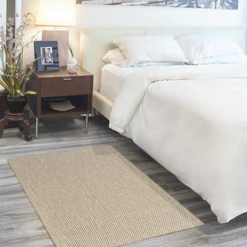 Bedroom scene with a Nourison Courtyard Jute Ivory rug, white bedding, and a dark wood nightstand.