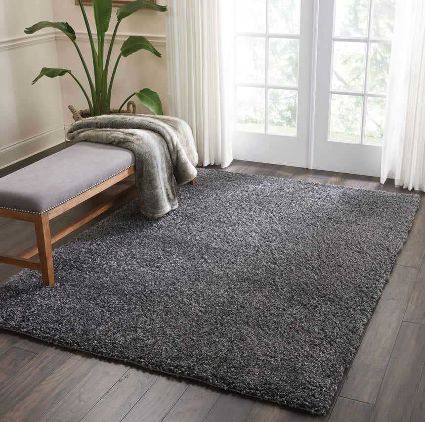 Bright room with Nourison Malibu Shag dark grey rug, wood floors, bench, and plant. Soft, cozy feel.