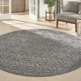 Modern living room with a round Nourison Cozumel Dark Grey rug, gray chair, and light wood floors.