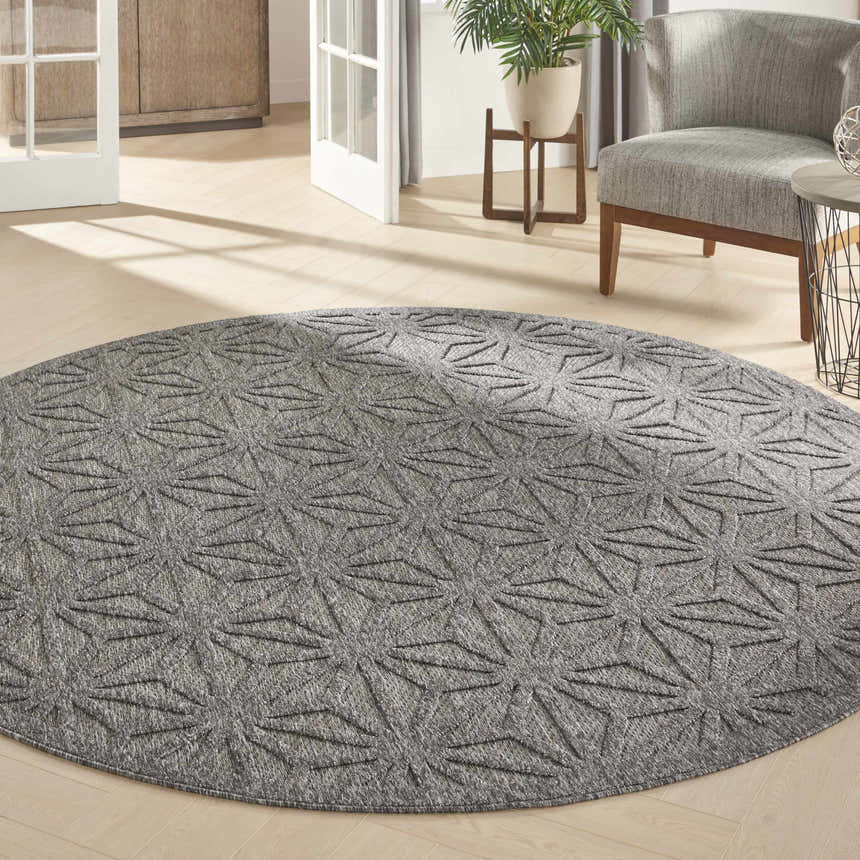 Modern living room with a round Nourison Cozumel Dark Grey rug, gray chair, and light wood floors.